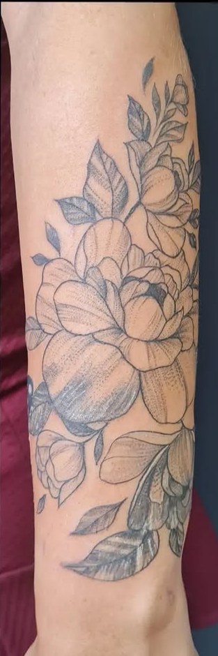 Depois: floral delicado cobrindo a tatuagem antiga no antebraço