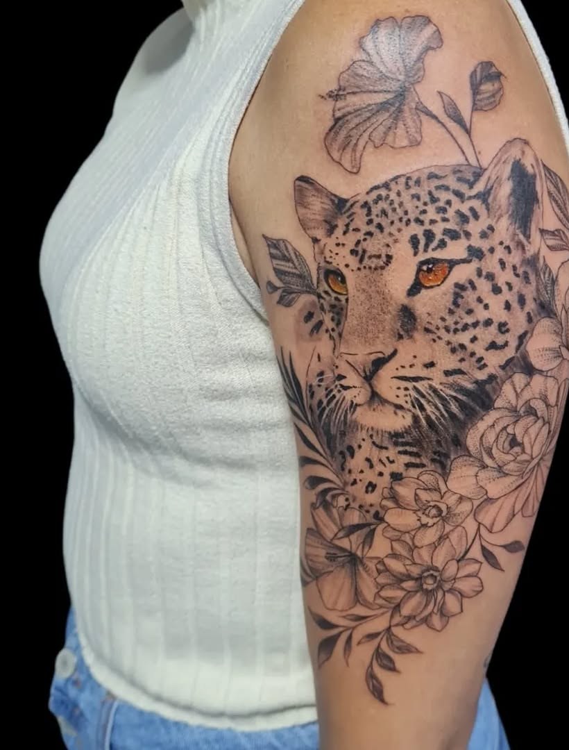 Tatuagem de onça com flores no ombro e braço