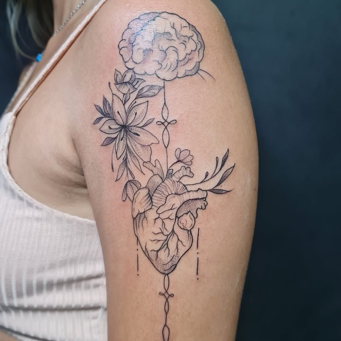 Tatuagem fine line de coração anatômico com flores no braço