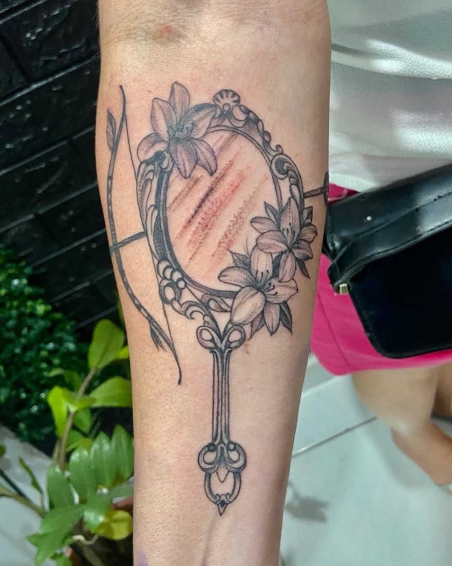 Tatuagem de espelho com flores em homenagem aos orixás
