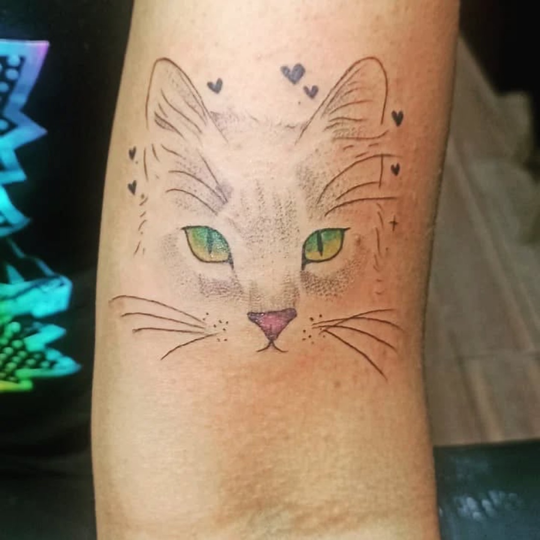 Tatuagem de gato com olhos verdes e traço delicado