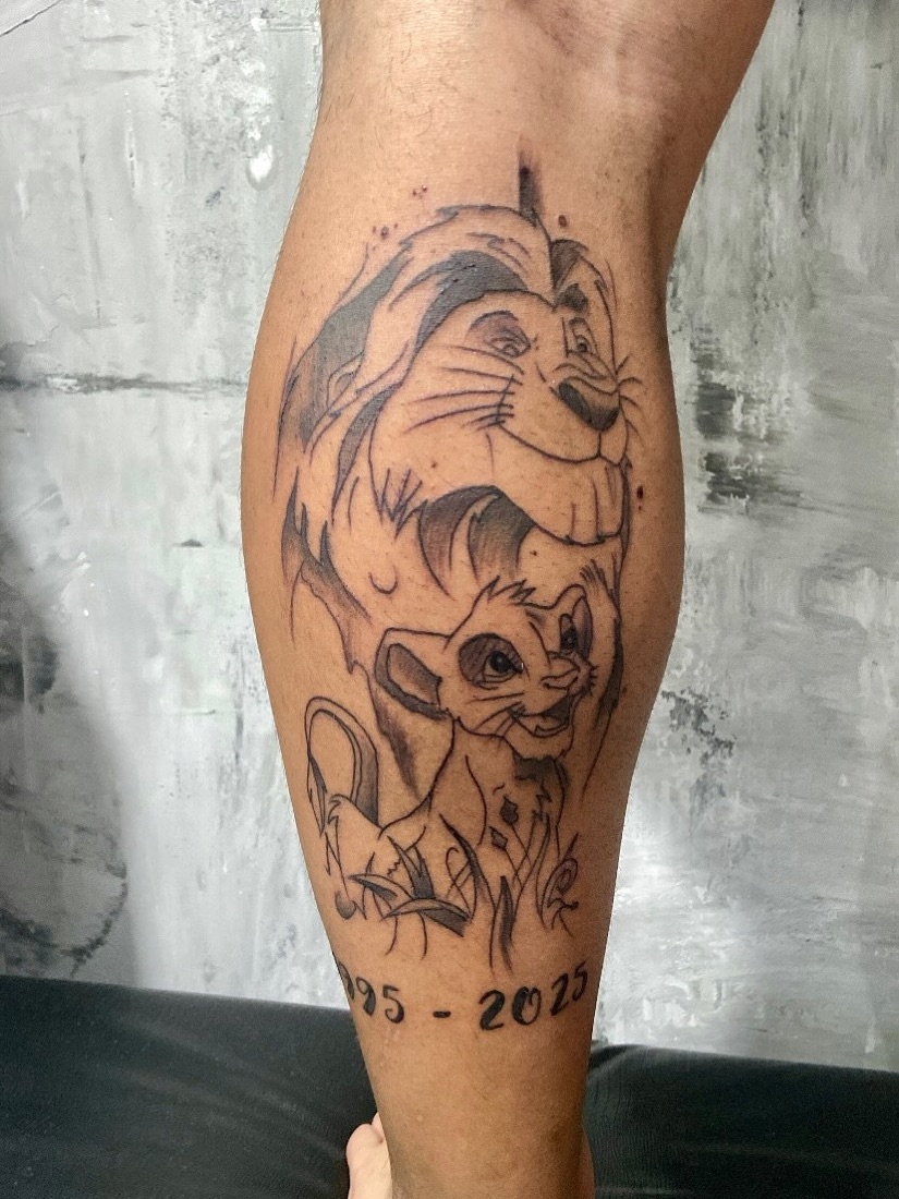 Tatuagem de leão e filhote em homenagem ao filho na canela