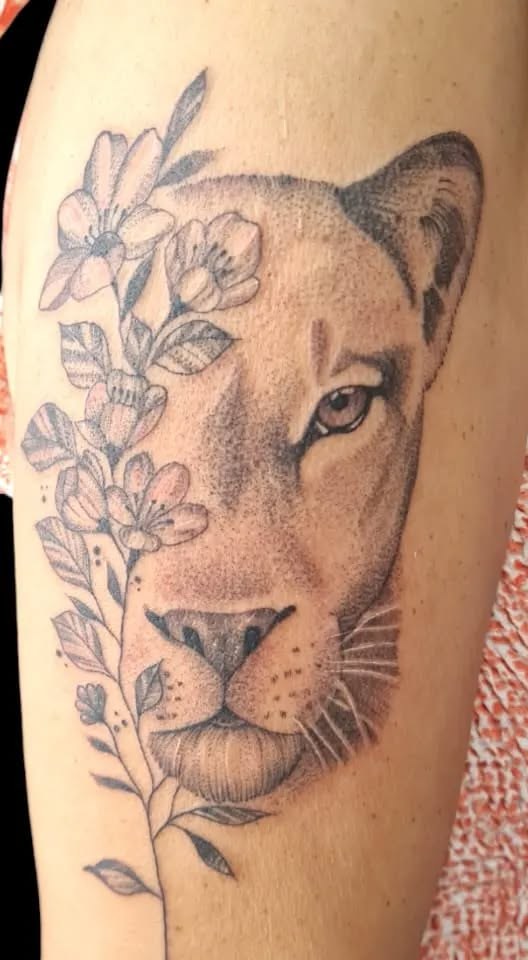 Tatuagem de leoa com flores em preto e cinza
