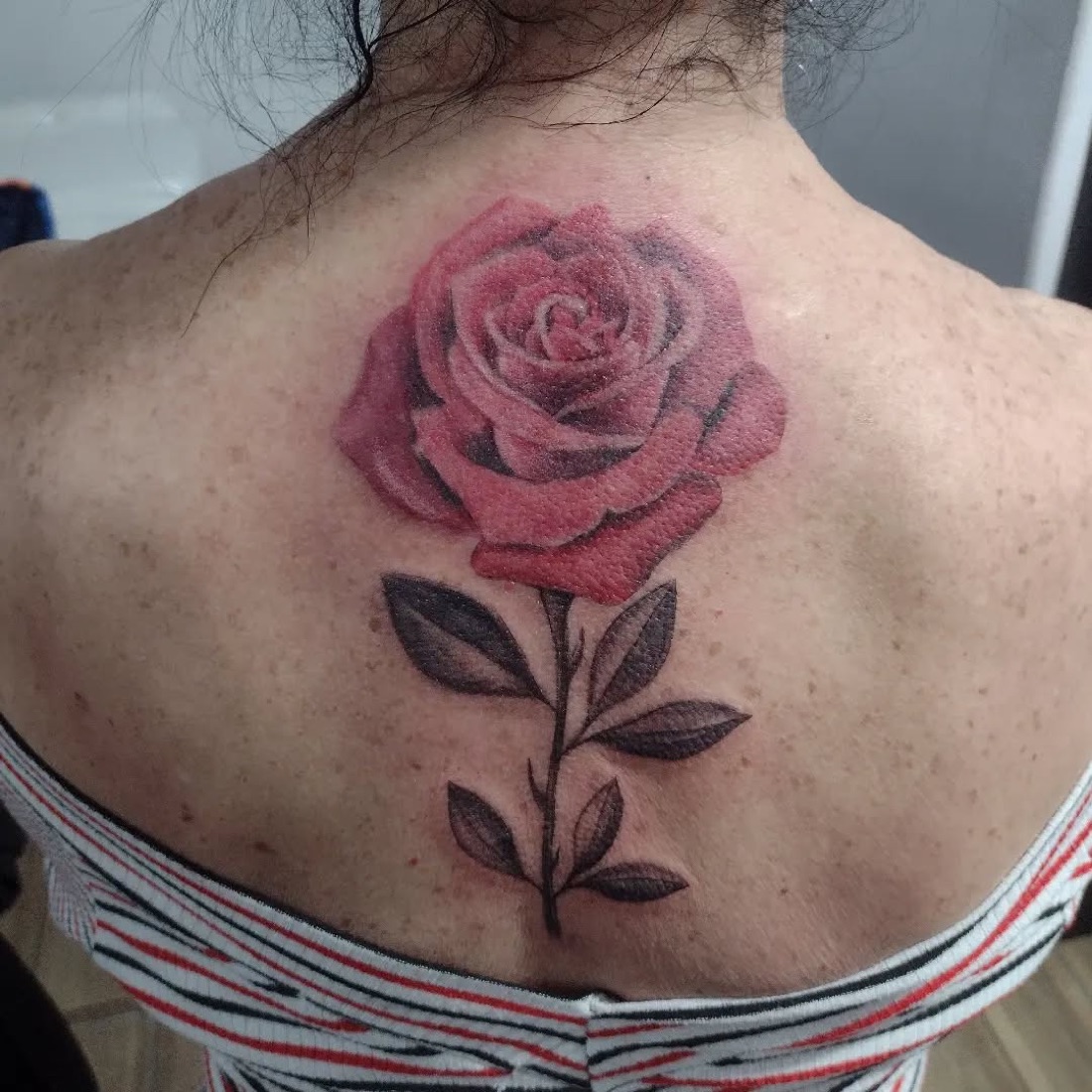Tatuagem colorida de rosa vermelha na nuca