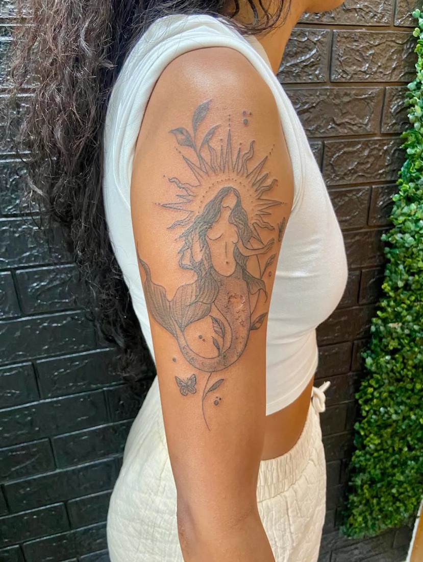 Tatuagem religiosa sombreada com raios de luz no braço